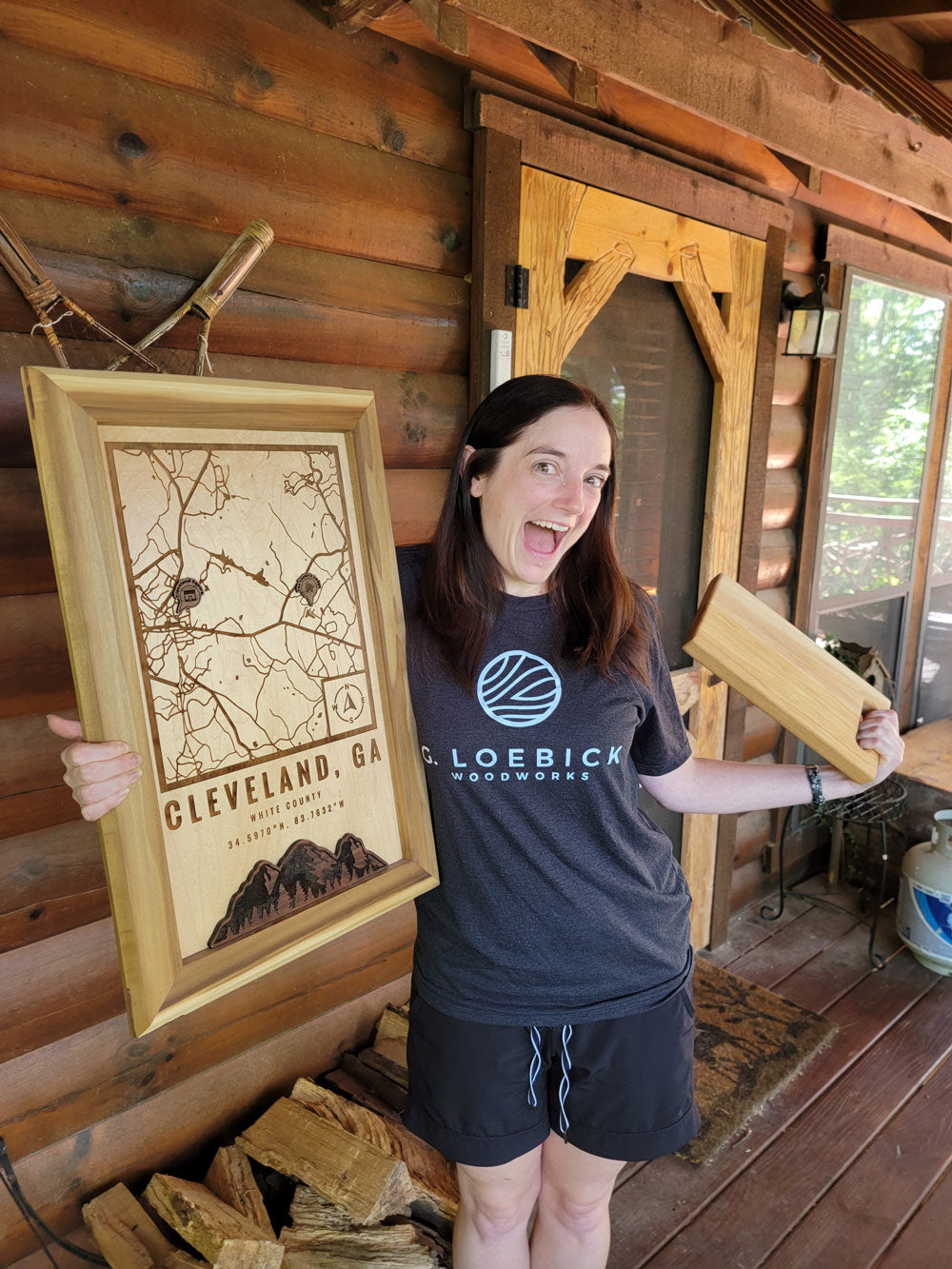 Happy woman holding a custom location wood map from G. Loebick Woodworks
