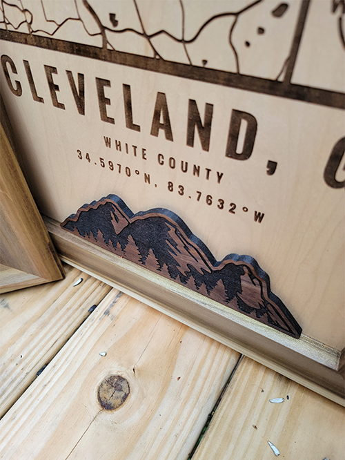 Mountain footer graphic on a custom location wood map from G. Loebick Woodworks